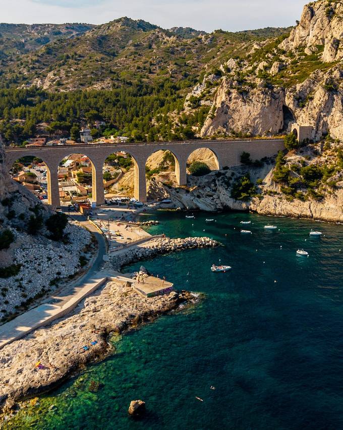 Calanque bordée de falaises traversée par un viaduc en pierre