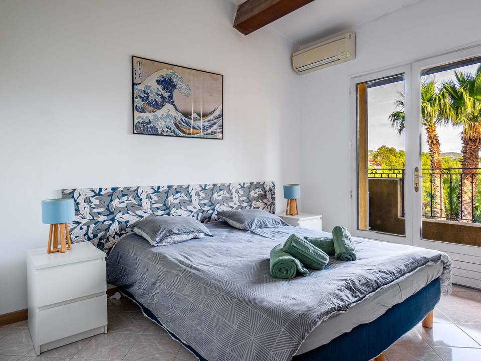 Chambre lumineuse ouverte sur un jardin planté de palmiers