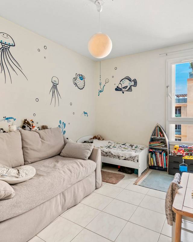 Chambre d'enfant avec canapé, fresque marine peinte au mur et coin jeux