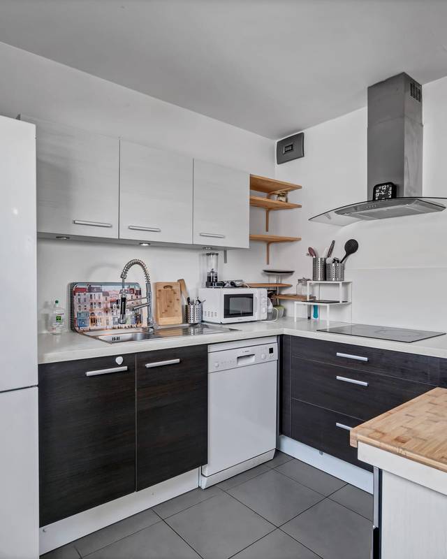 Cuisine équipée blanche et noire avec réfrigérateur américain et hotte inox