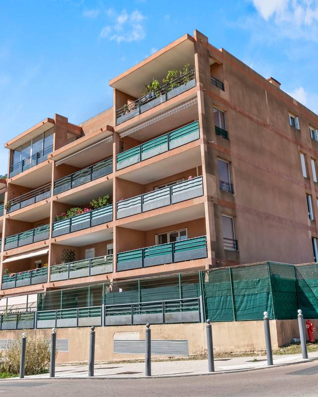 Résidence récente en briques avec balcons filants sous un ciel bleu