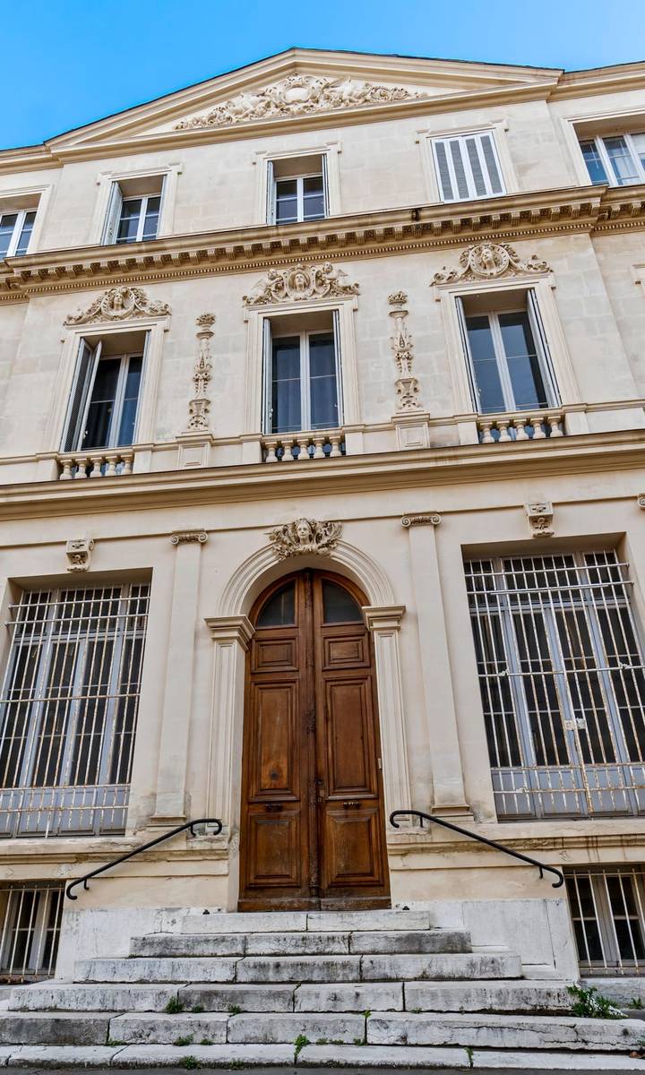 Façade d'un hôtel particulier marseillais en pierre avec porte cintrée en bois