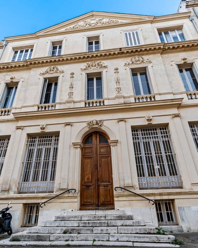 Façade d'un hôtel particulier en pierre avec porte en bois cintrée et perron