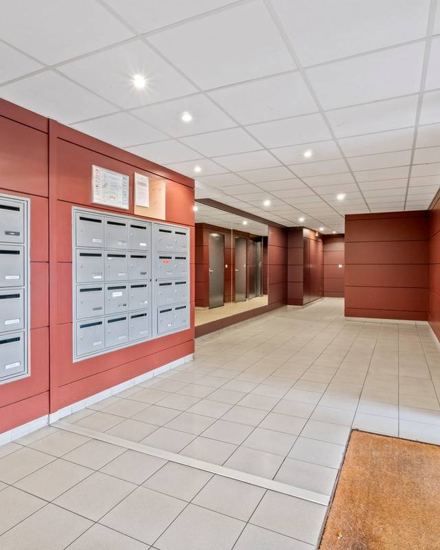 Hall d'entrée de résidence avec boîtes aux lettres et murs rouge brique
