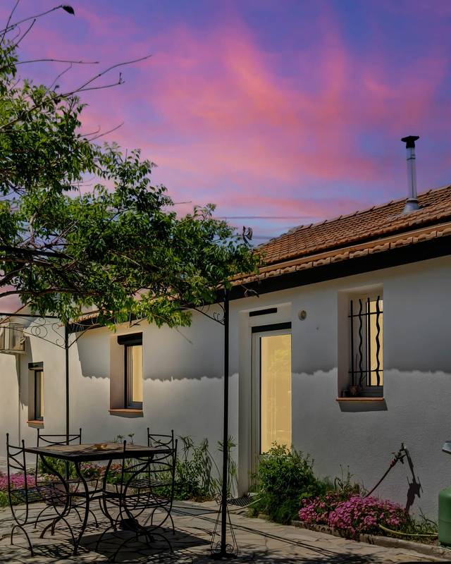 Cour arborée d'une maison basse au crépuscule sous un ciel rose