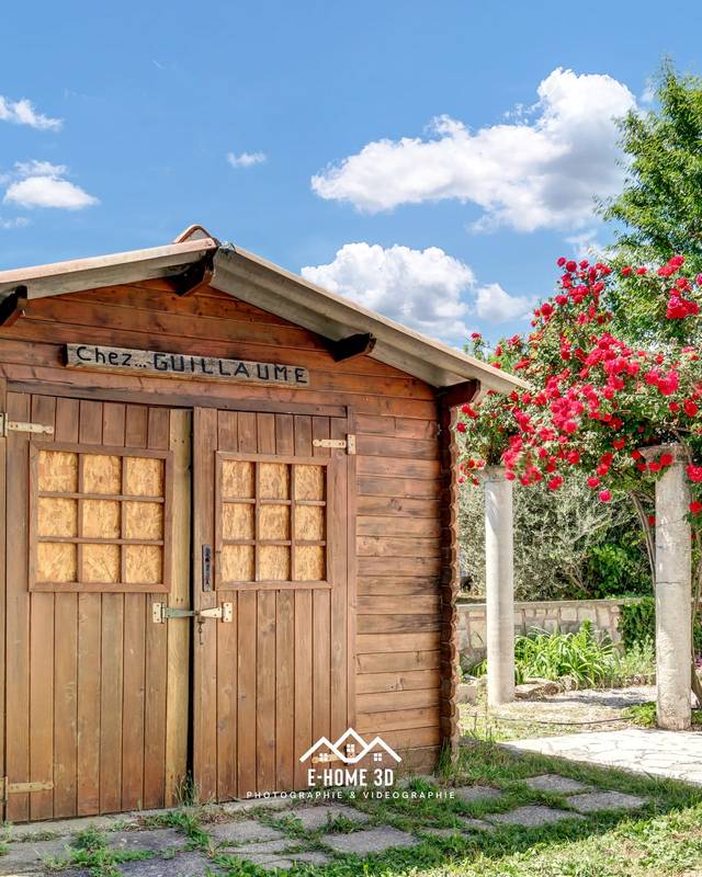 Abri de jardin en bois à double porte, rosiers et pas japonais dans la pelouse