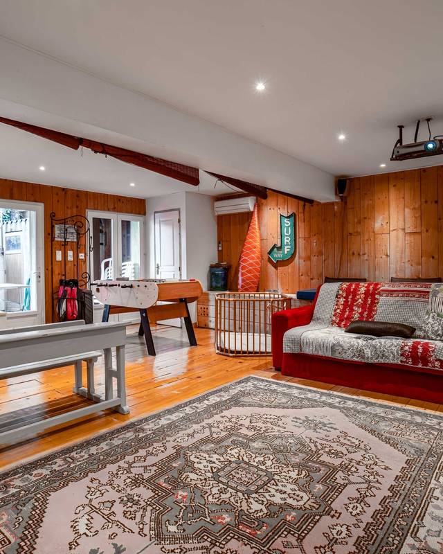 Salle de jeux lambrissée avec baby-foot, lits superposés et grand tapis