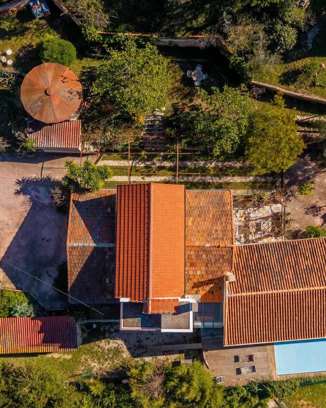 Vue zénithale d'une maison aux toits de tuiles avec piscine et terrain arboré