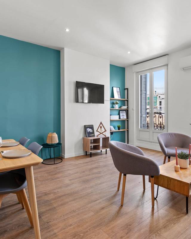 Coin repas avec table en bois, mur bleu canard et parquet clair